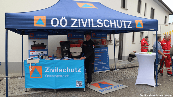 Messestand des Oberösterreichischen Zivilschutzes mit einem Mitarbeiter und Informationsmaterial zu Warn- und Alarmsignalen und krisenfestem Haushalt.